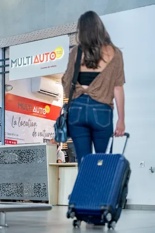 Customer with her suitcase arriving at the MultiAuto desk at Roland Garros airport in Réunion