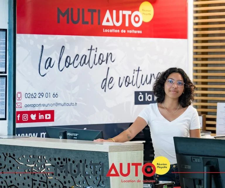 Hôtesse Multi Auto prête à accueillir les voyageurs au comptoir de location de voiture de l'aéroport Roland Garros à La Réunion